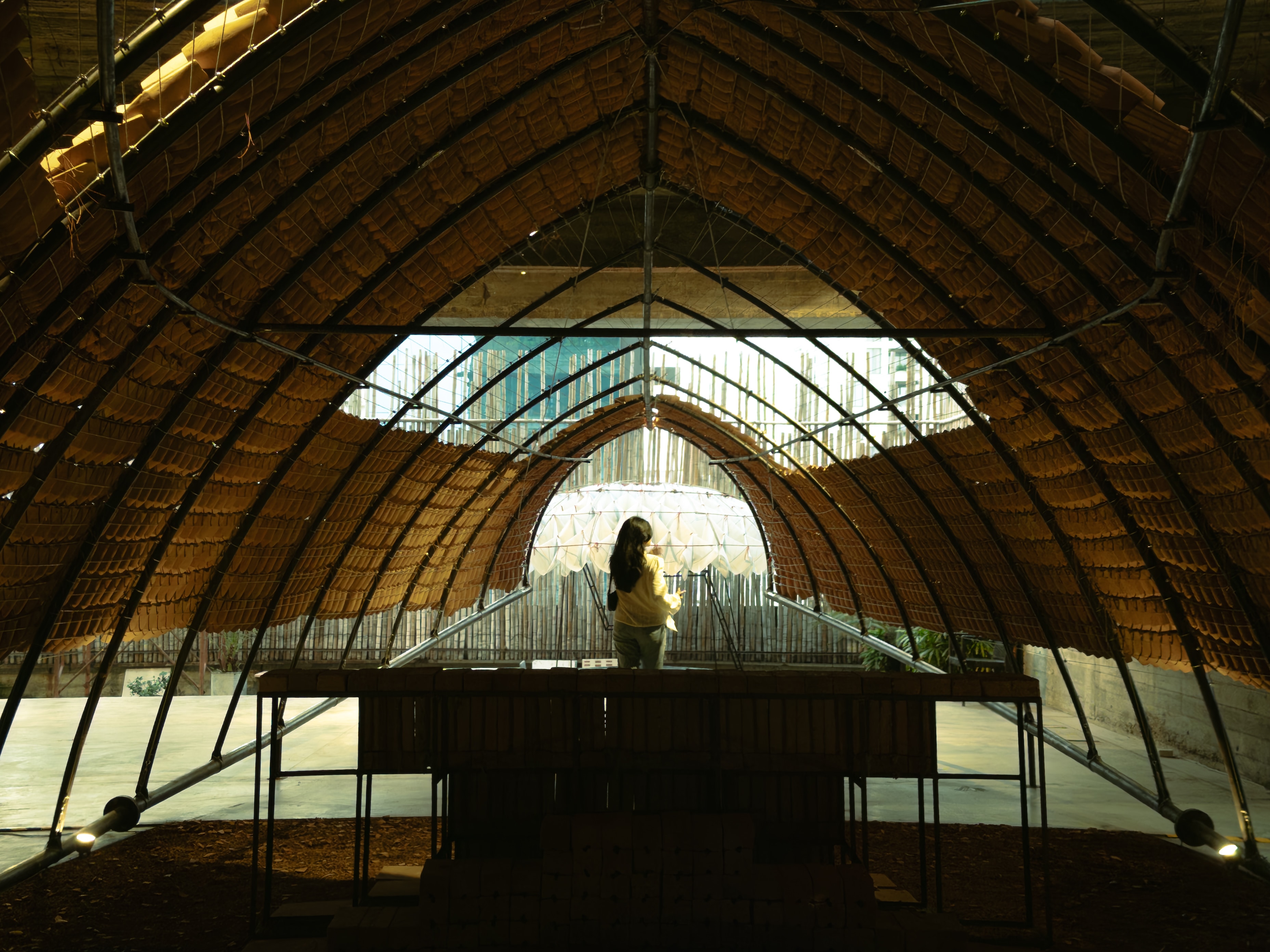 A person standing beneath a vaulted bamboo structure