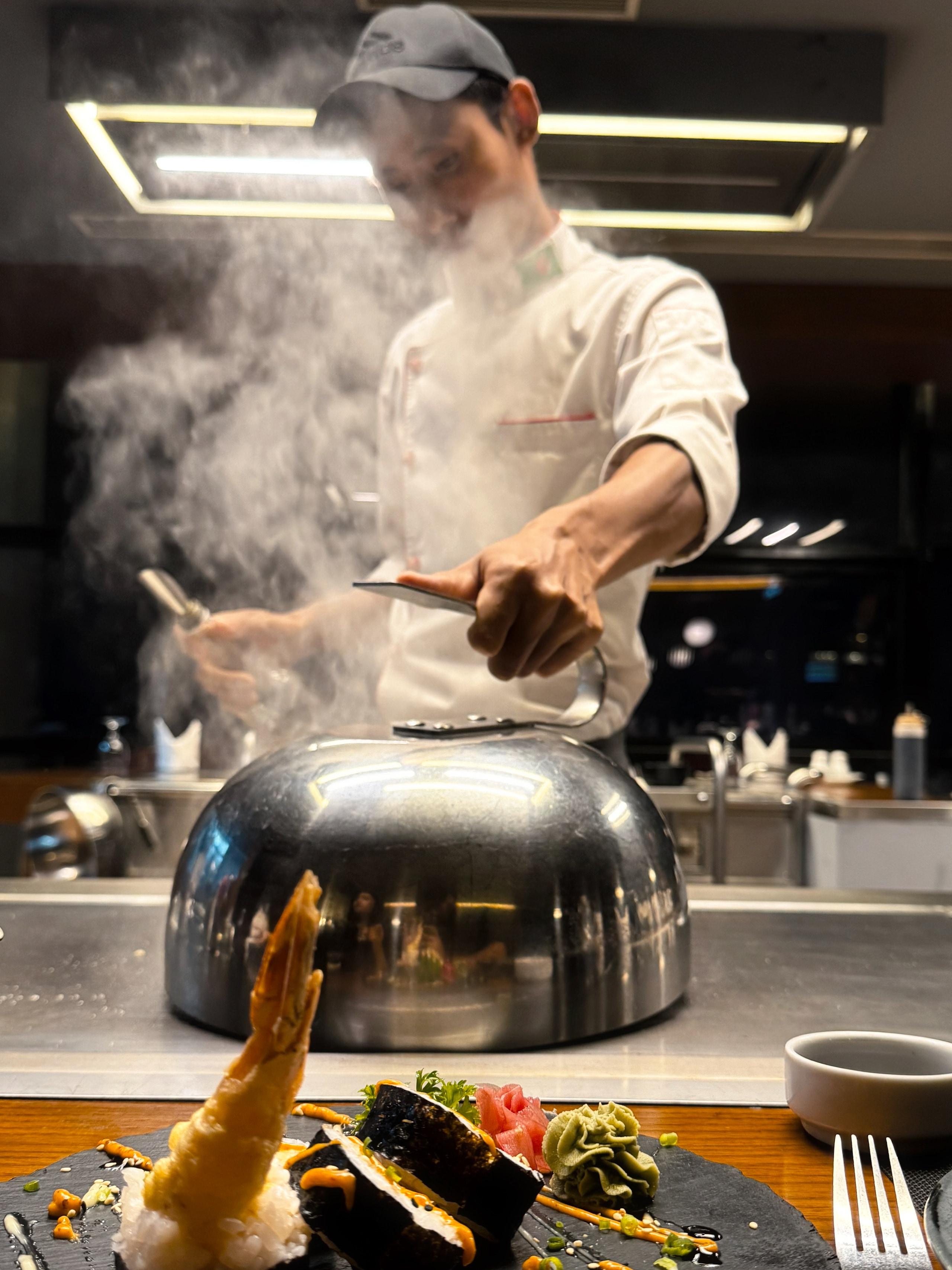 A chef cooking behind a cloud of steam